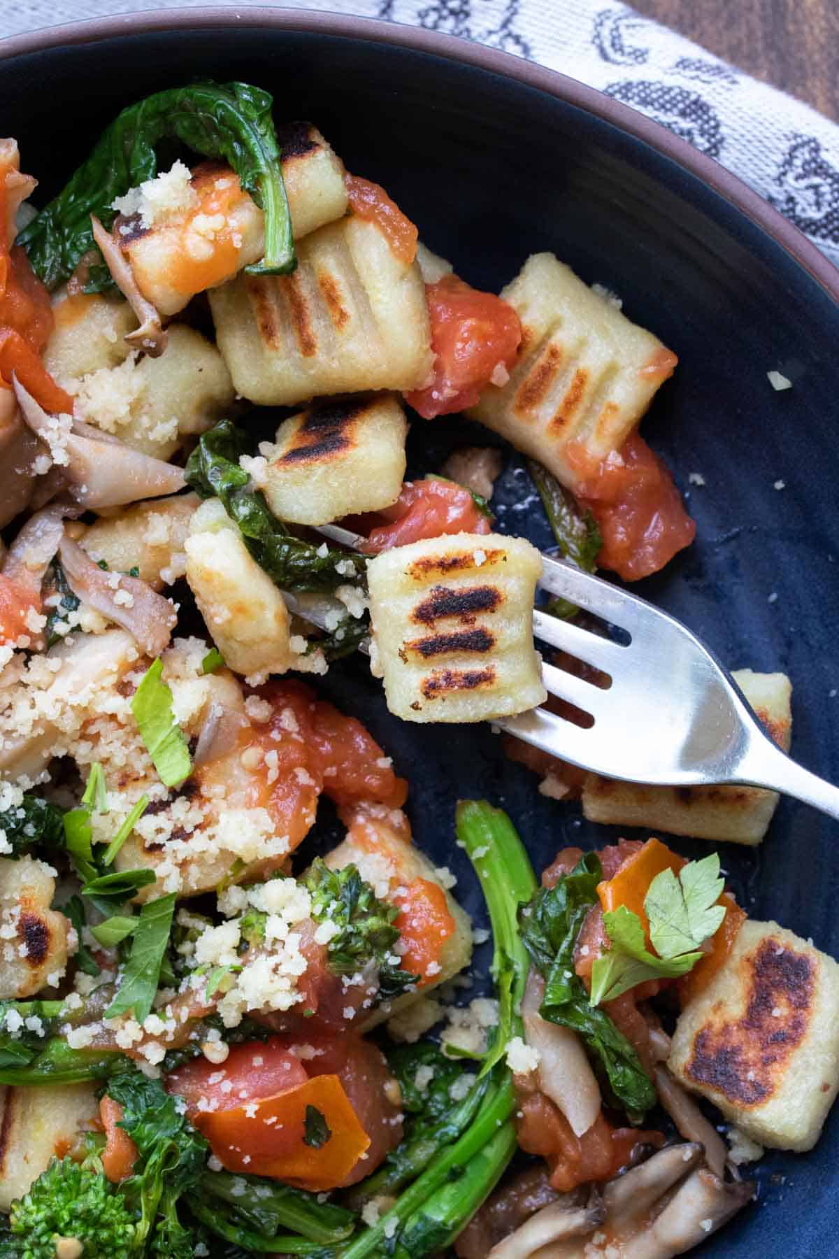 Fork getting a bite of gnocchi from a bowl.