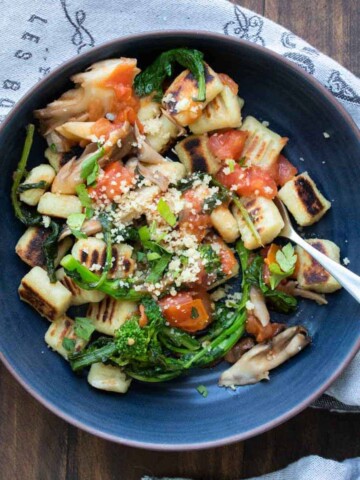 Tomatoes and broccoli over a bowl of gnocchi.