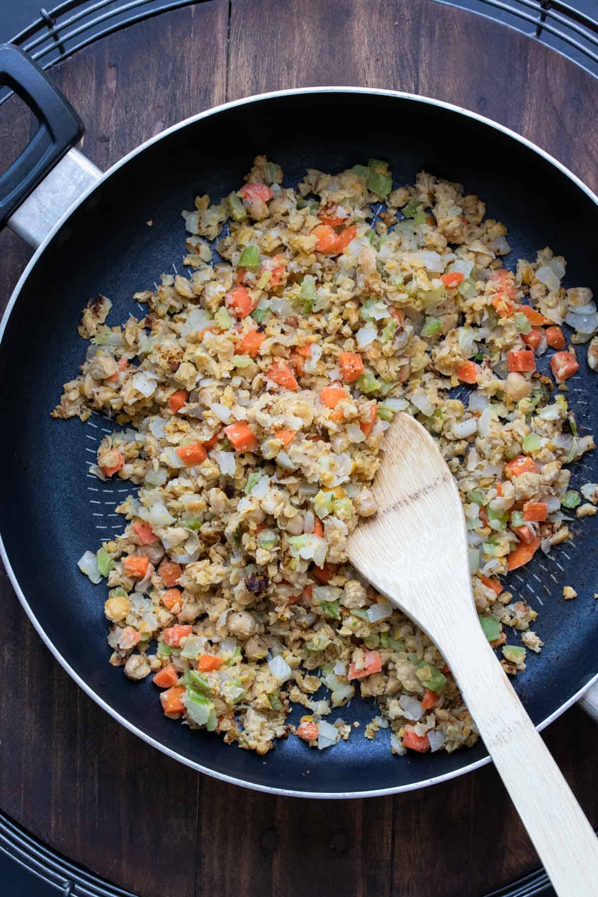 Wooden spoon mixing stuffing ingredients in a pan