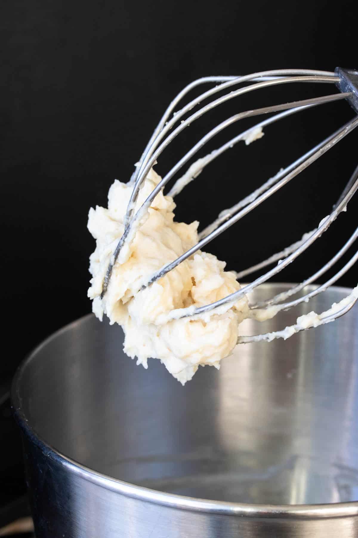 Whisk attachment on a stand mixer with mashed potatoes on it