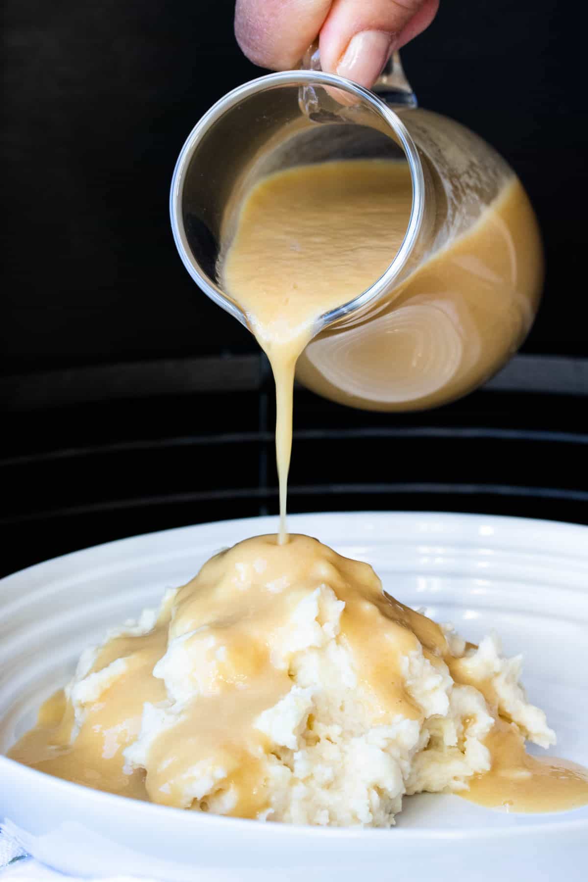 Gravy being poured over a pile of mashed potatoes