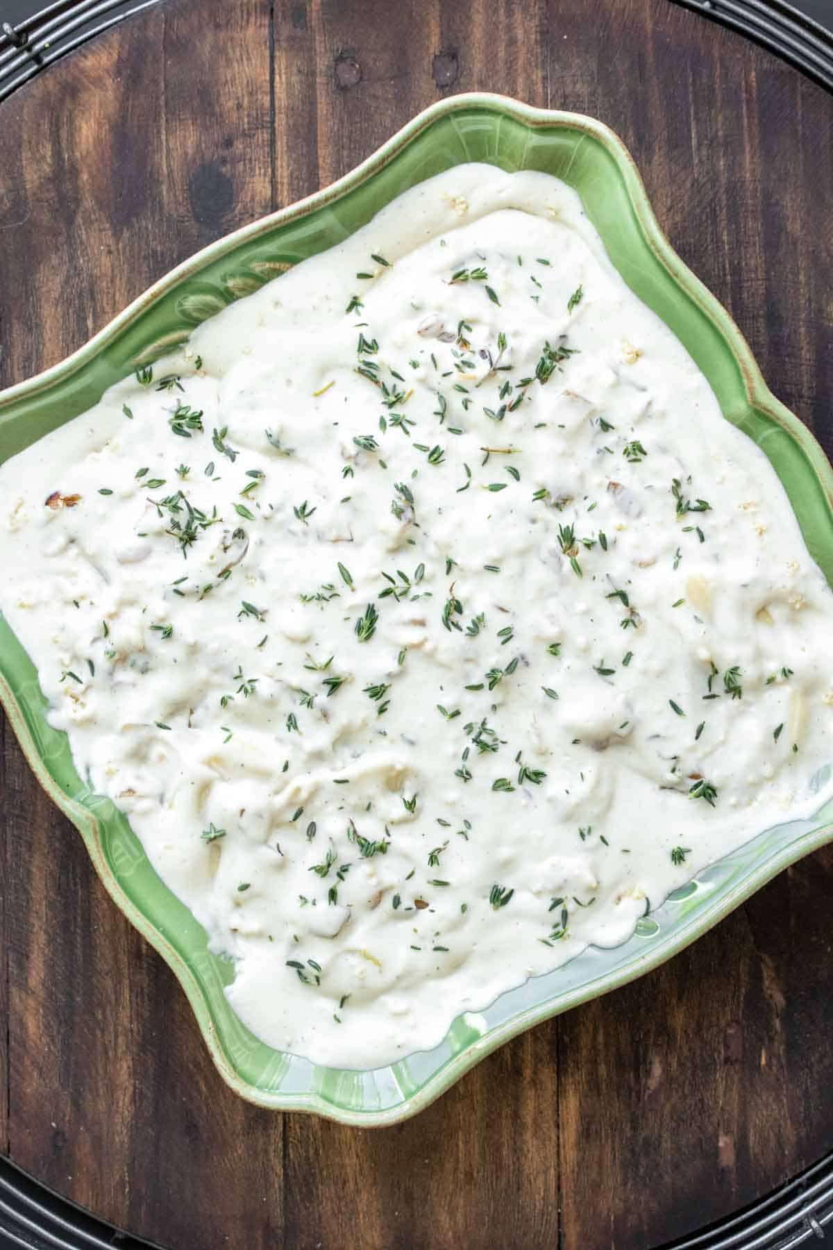 Unbaked scalloped potatoes in a green baking dish.