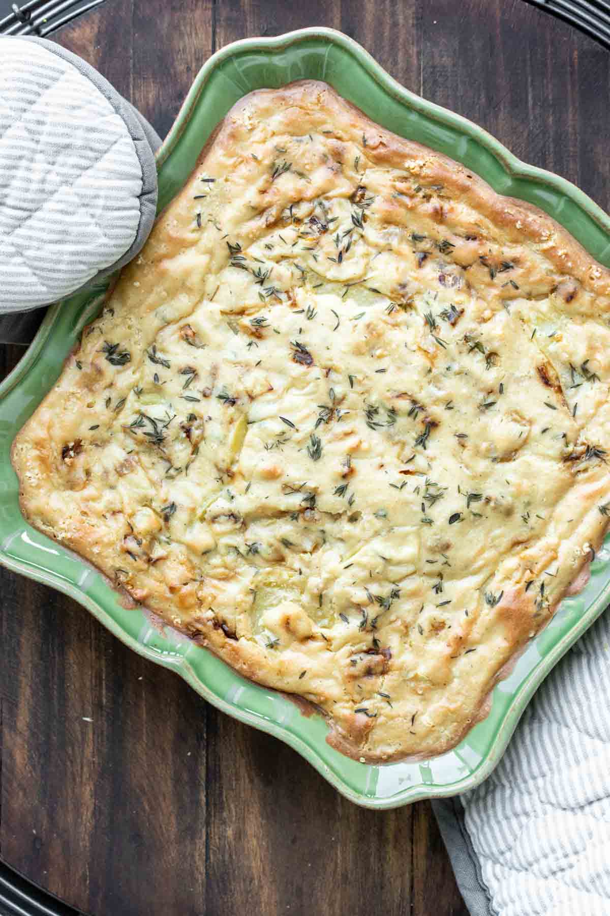 Golden baked scalloped potatoes in a green dish.