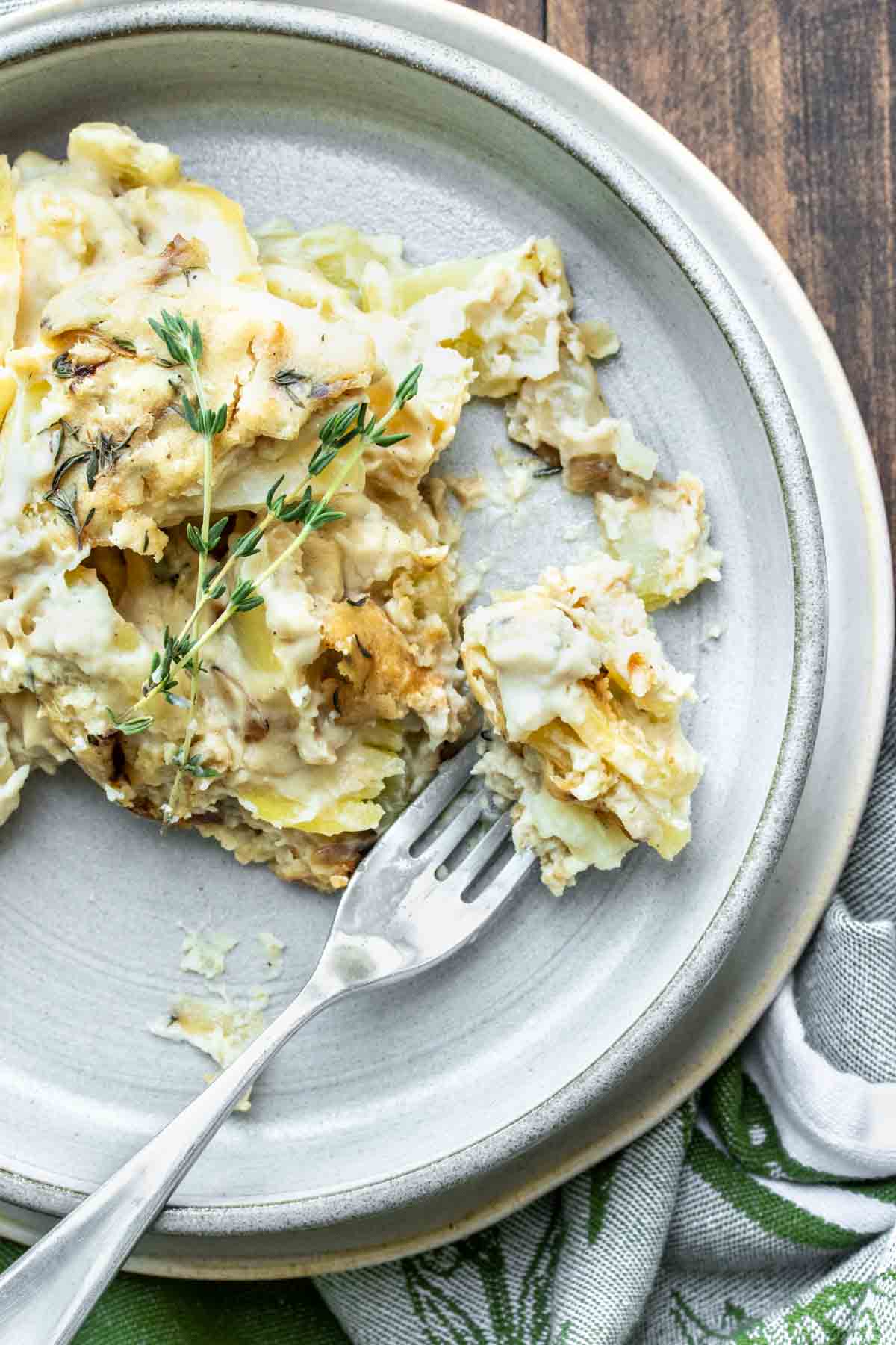 Fork getting a bite out of a plate of scalloped potatoes.