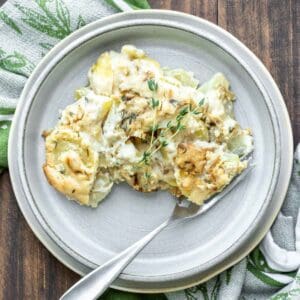 Grey plate with scalloped potatoes and a fork on it.