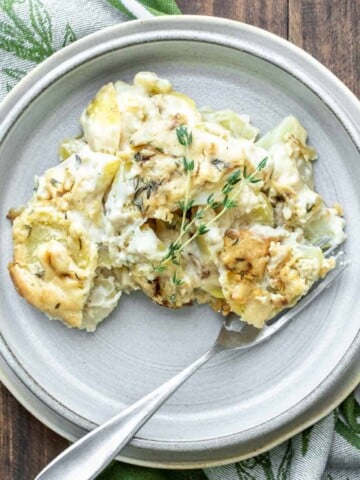 Grey plate with scalloped potatoes and a fork on it.