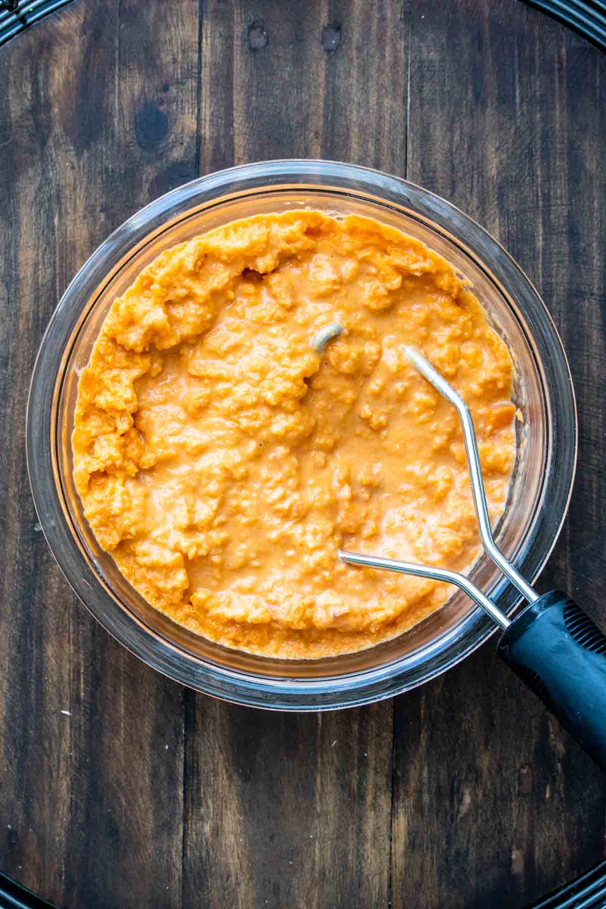 Potato masher mixing sweet potato casserole filling.