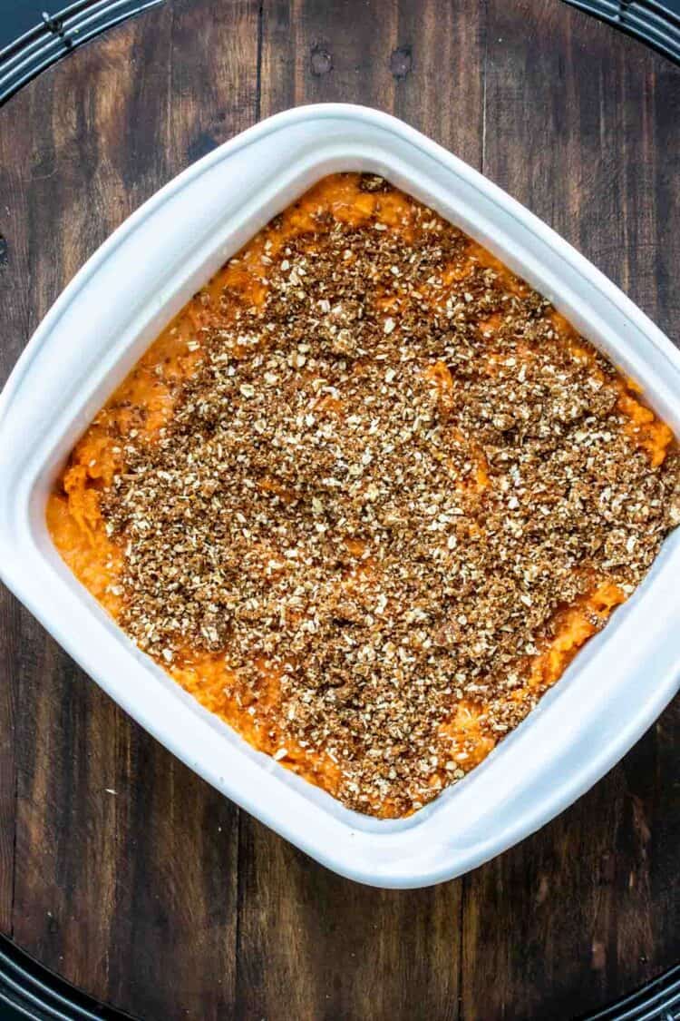 Uncooked sweet potato casserole with pecan topping in a white baking dish.