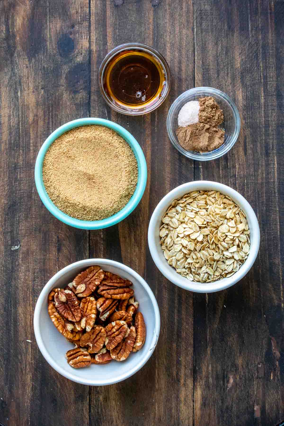 Bowls on a wooden surface filled with ingredients to make a sweet pecan topping.