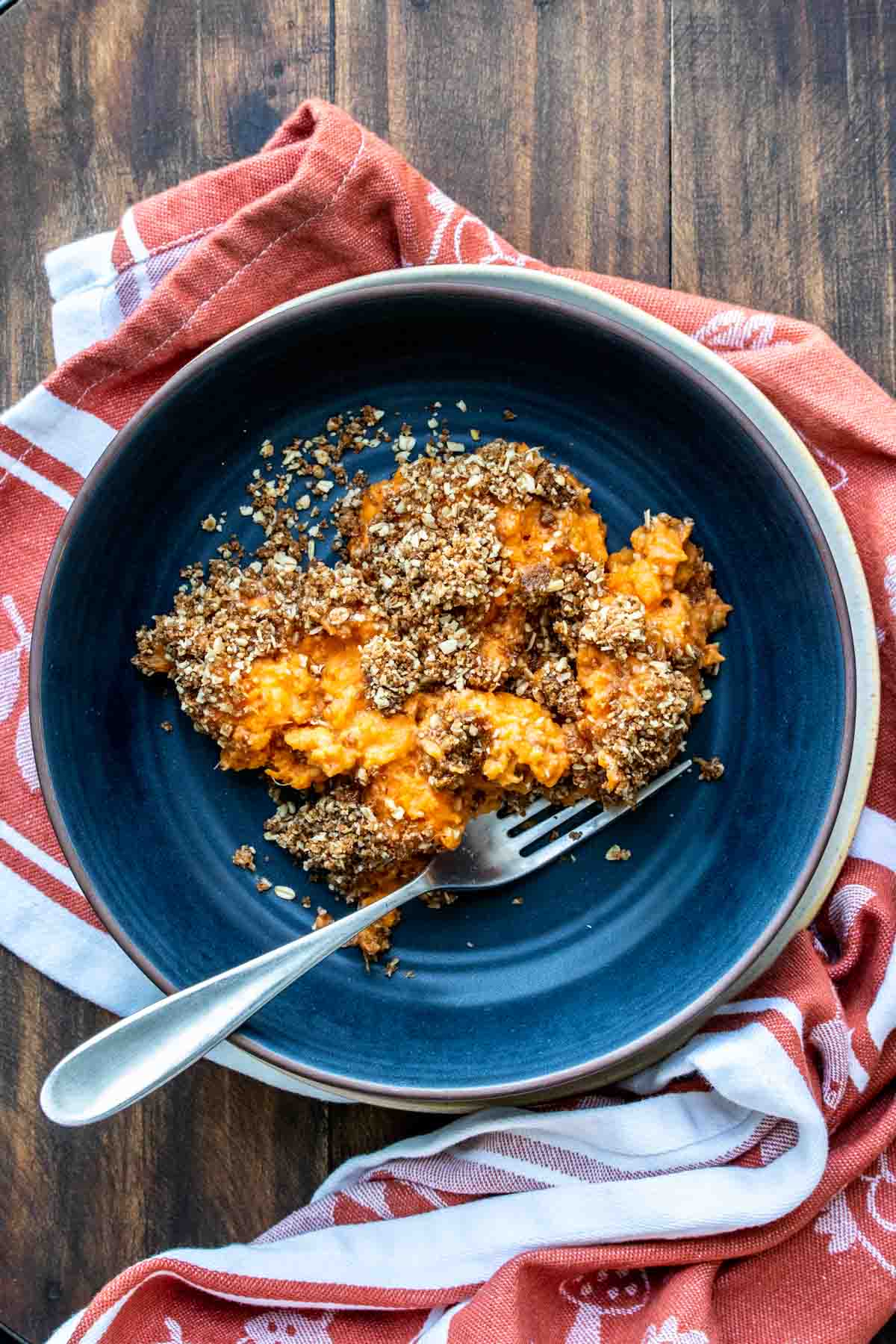 Sweet potato casserole with pecan topping on a dark blue plate