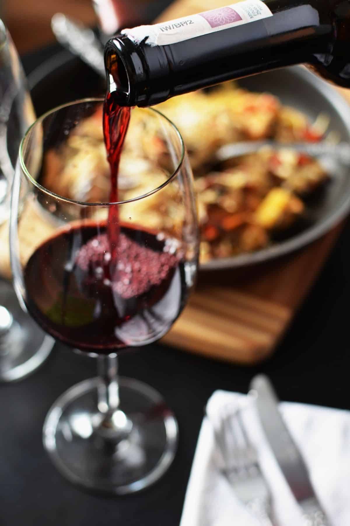 A bottle pouring red wine into a glass