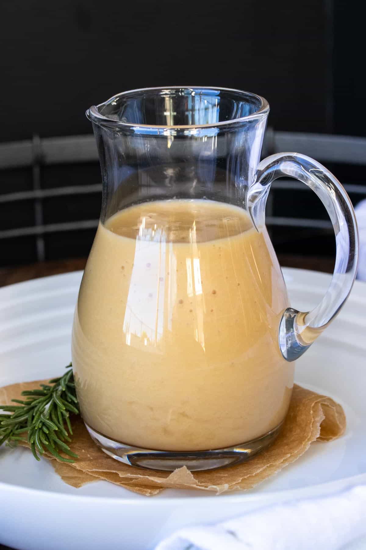 Glass pitcher filled with an onion grave on a white plate