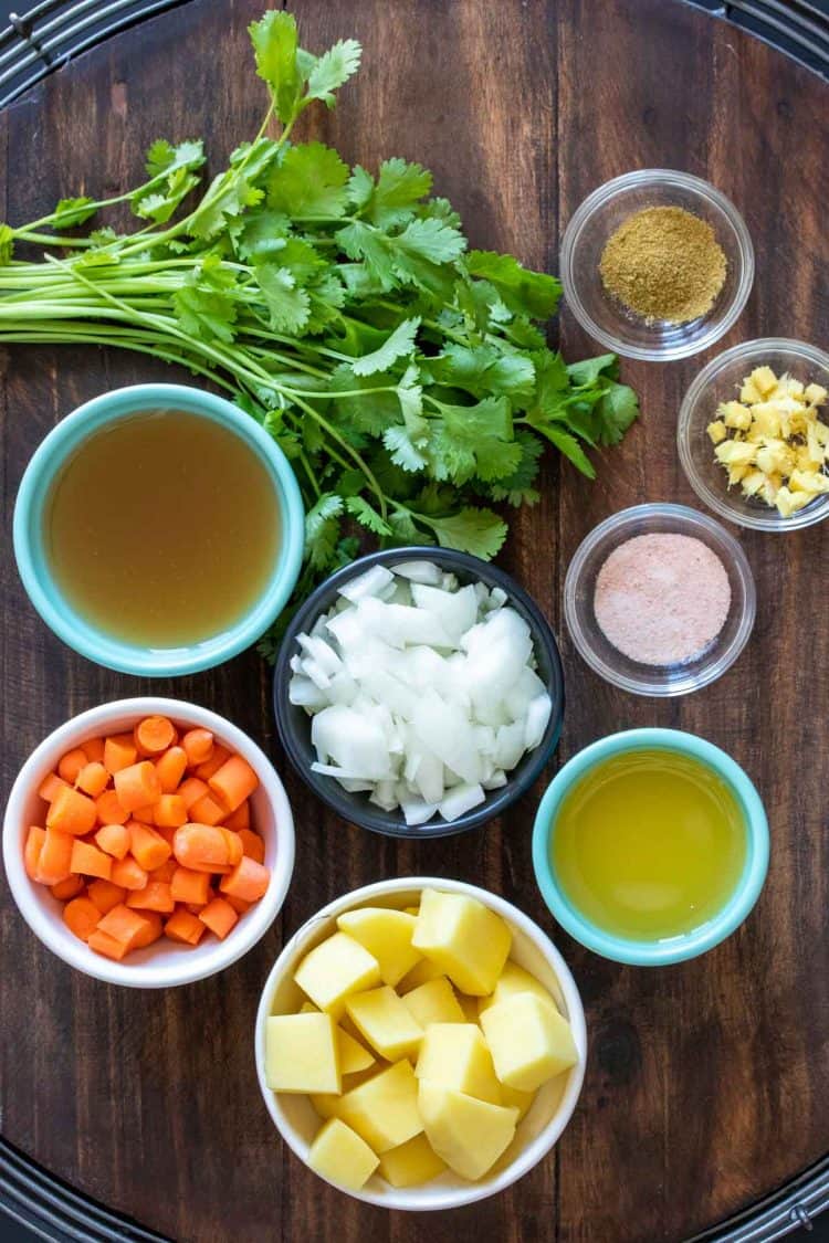 Different colored bowls with ingredients to make a carrot and potato soup