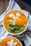 Spoon getting a bite of carrot soup from a white bowl