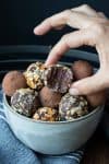 Hand taking a half eaten chocolate truffle from a grey bowl