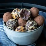 Grey bowl filled with chocolate truffles covered with toppings.