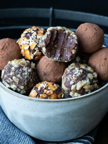 Grey bowl filled with chocolate truffles covered with toppings.