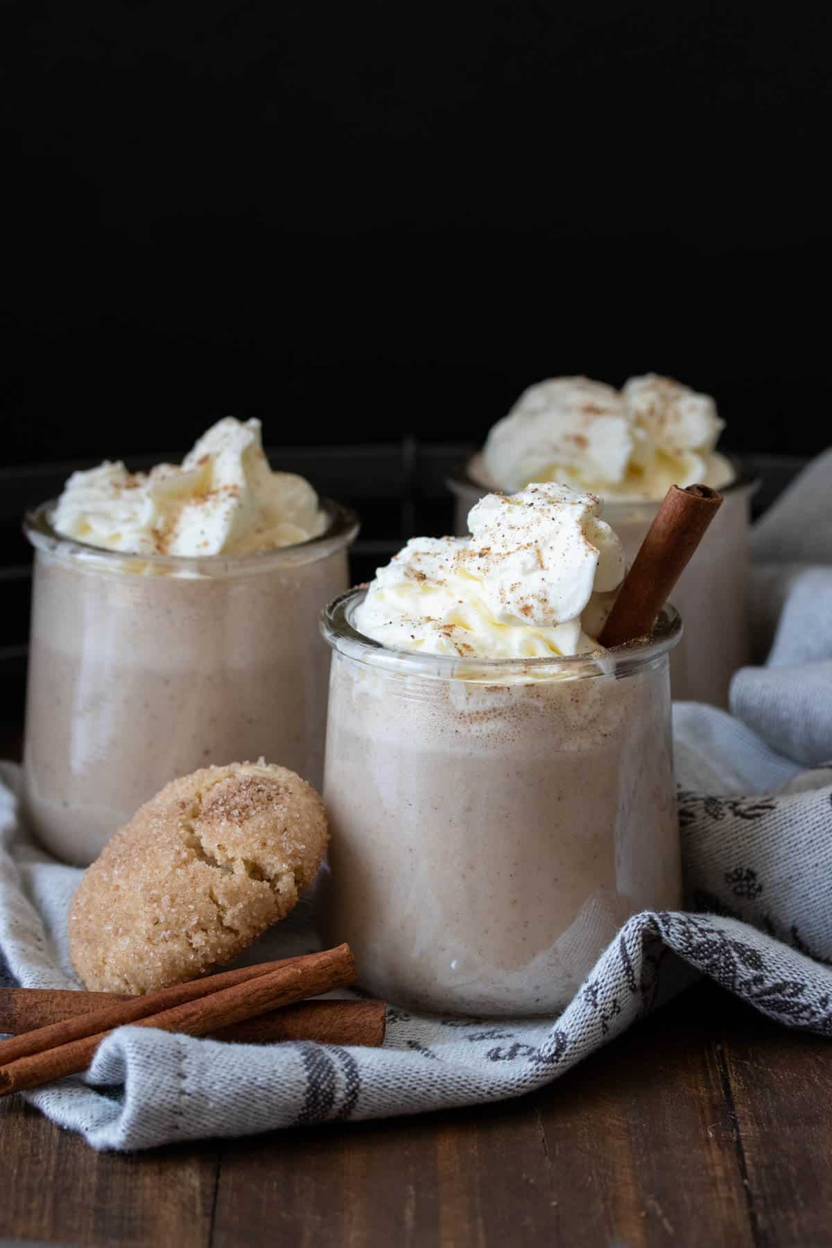 Three glass jars filled with eggnog and whipped cream