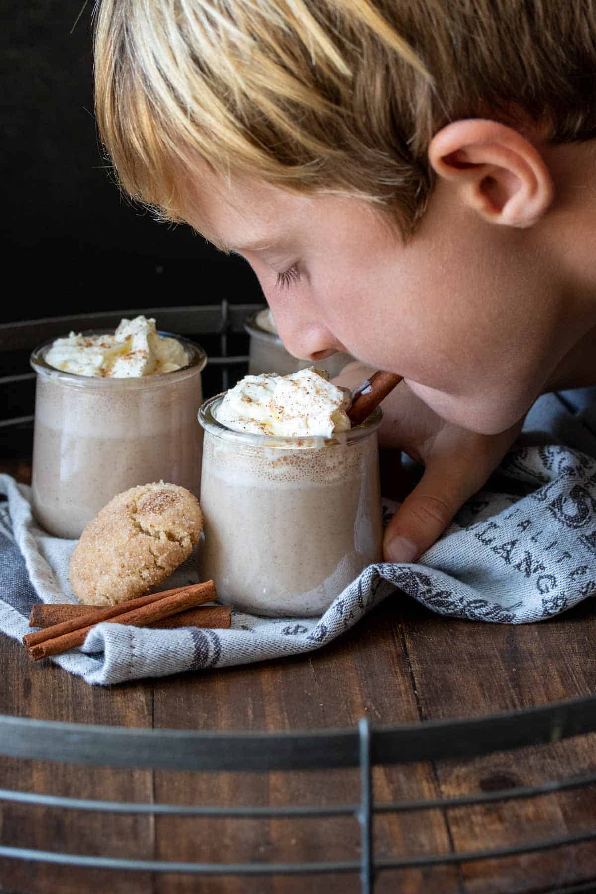 Boy drinking eggnog with whipped cream out of a jar.