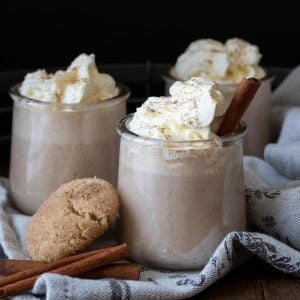 Whipped cream on top of eggnog in a glass jar.