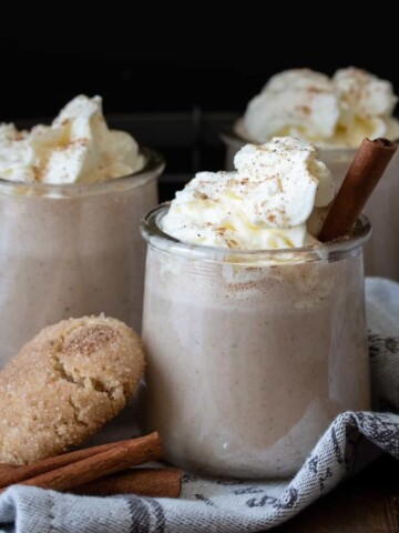 Whipped cream on top of eggnog in a glass jar.