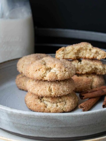 Grey plate with a pile of snickerdoodle cookies and cinnamon sticks