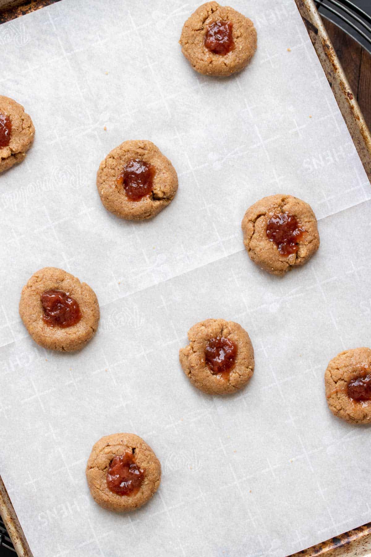 Cookie sheet with parchment paper and raw thumbprint cookies