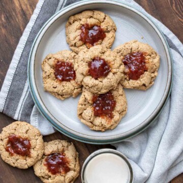Thumbprint cookies with berry jam on a grey plate on a wooden surface