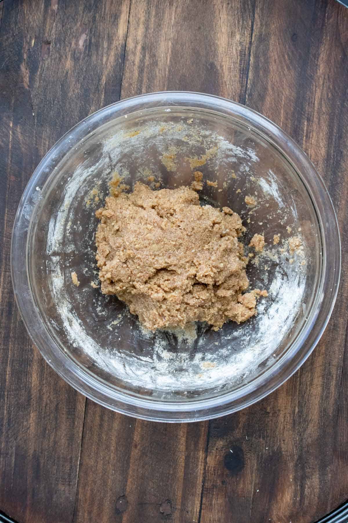 Cookie dough ball in a glass bowl on a wooden surface