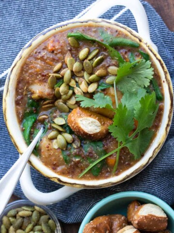 Bowl of sweet potato soup topped with pretzels and pumpkin seeds