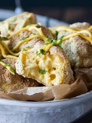 A pile of mac and cheese balls with crispy coating in a white bowl