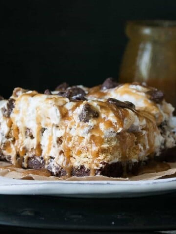 A layered dessert with chocolate bottom and whipped cream on top with caramel and chocolate chips