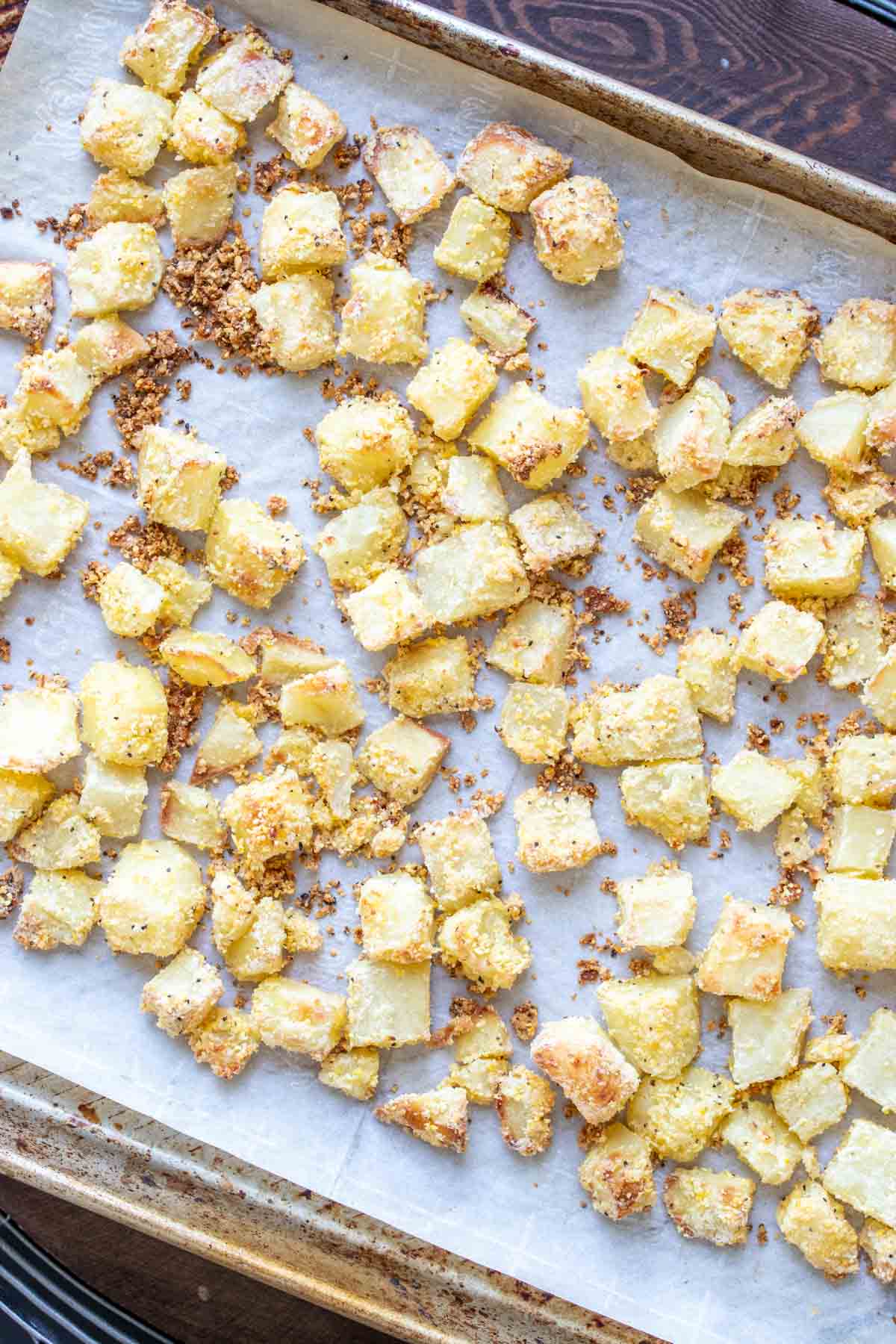 Baking sheet with parchment paper and baked crispy potato pieces