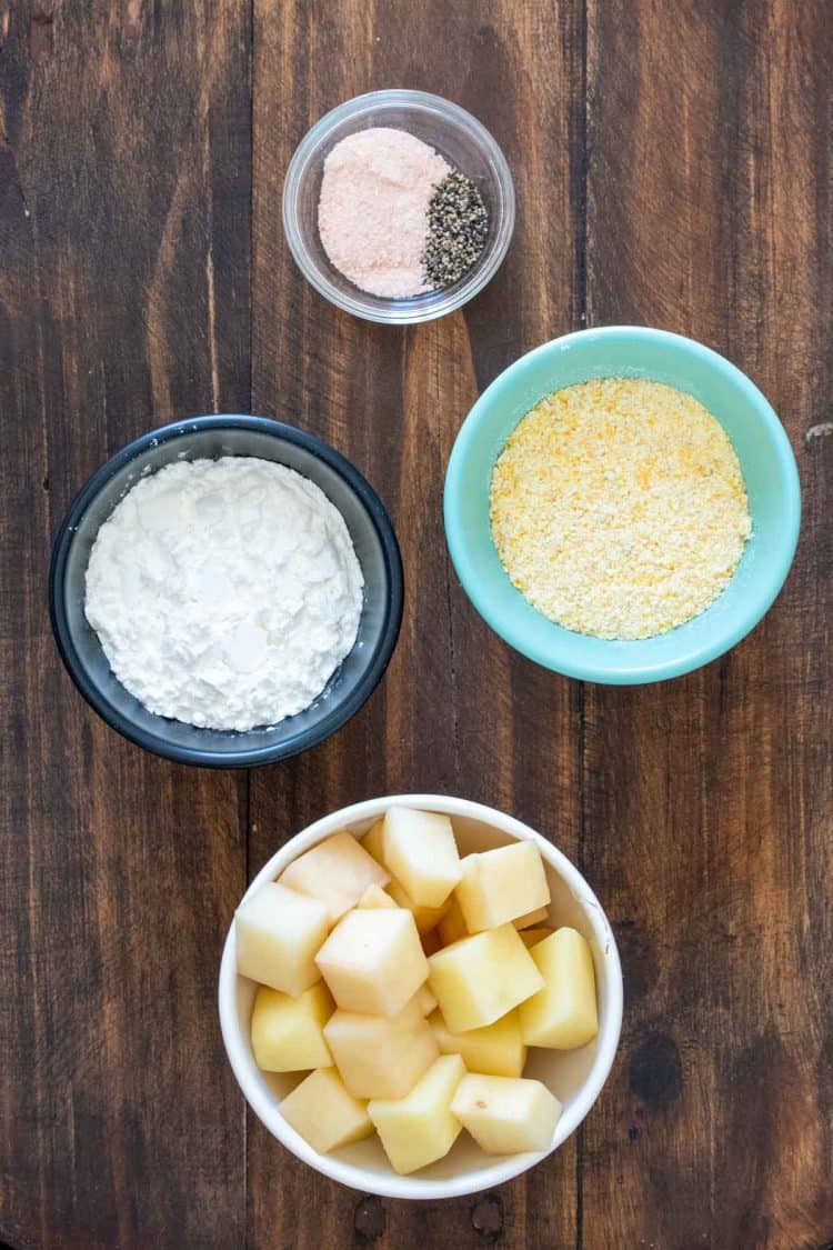 Bowls with cubed potatoes, cornmeal, cornstarch, salt and pepper