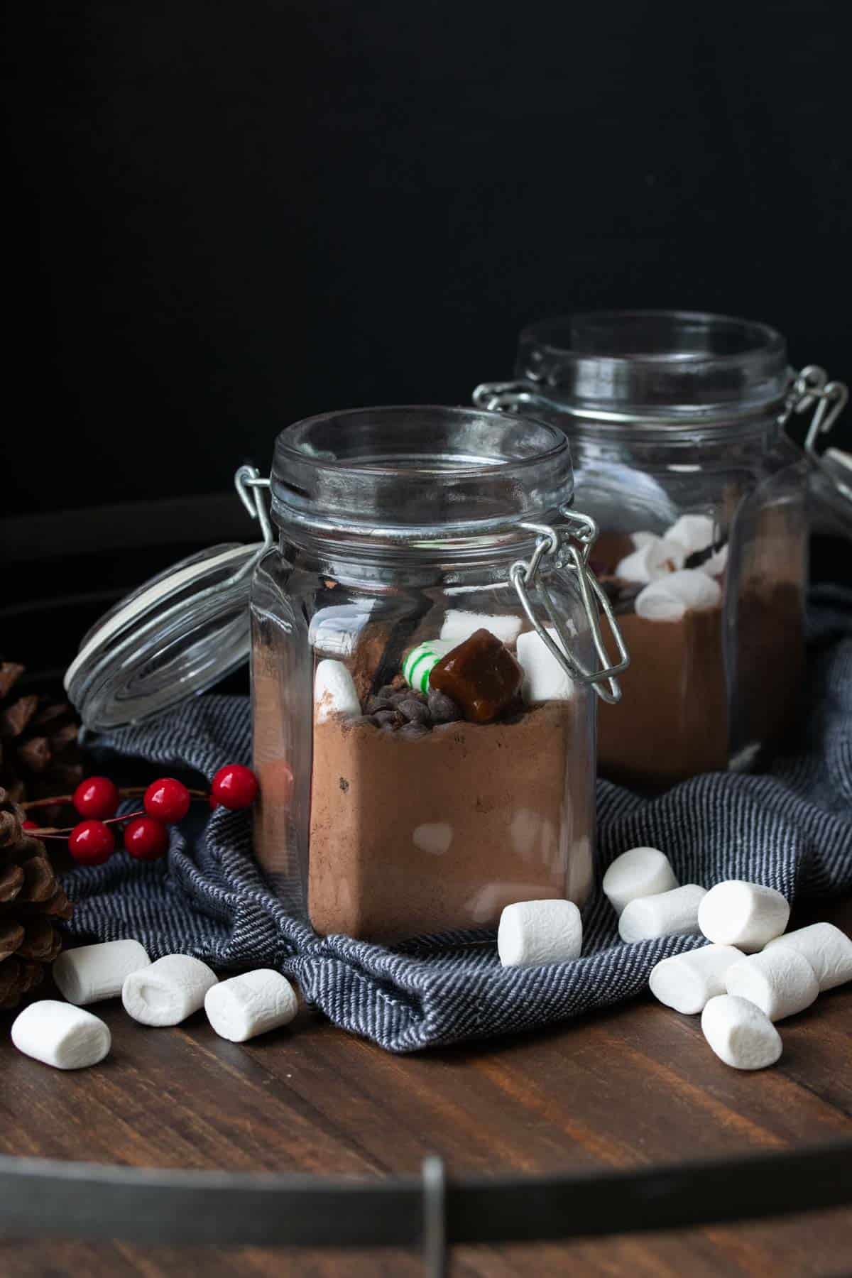 Two glass jars on a wooden tray filled with hot chocolate mix