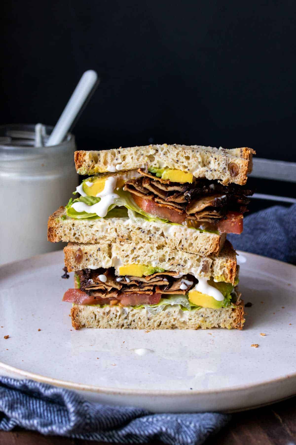 Two halves of a vegan BLT stacked on a plate