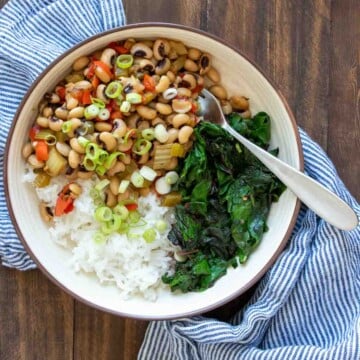 Cream bowl filled with rice, black eyed peas and swiss chard