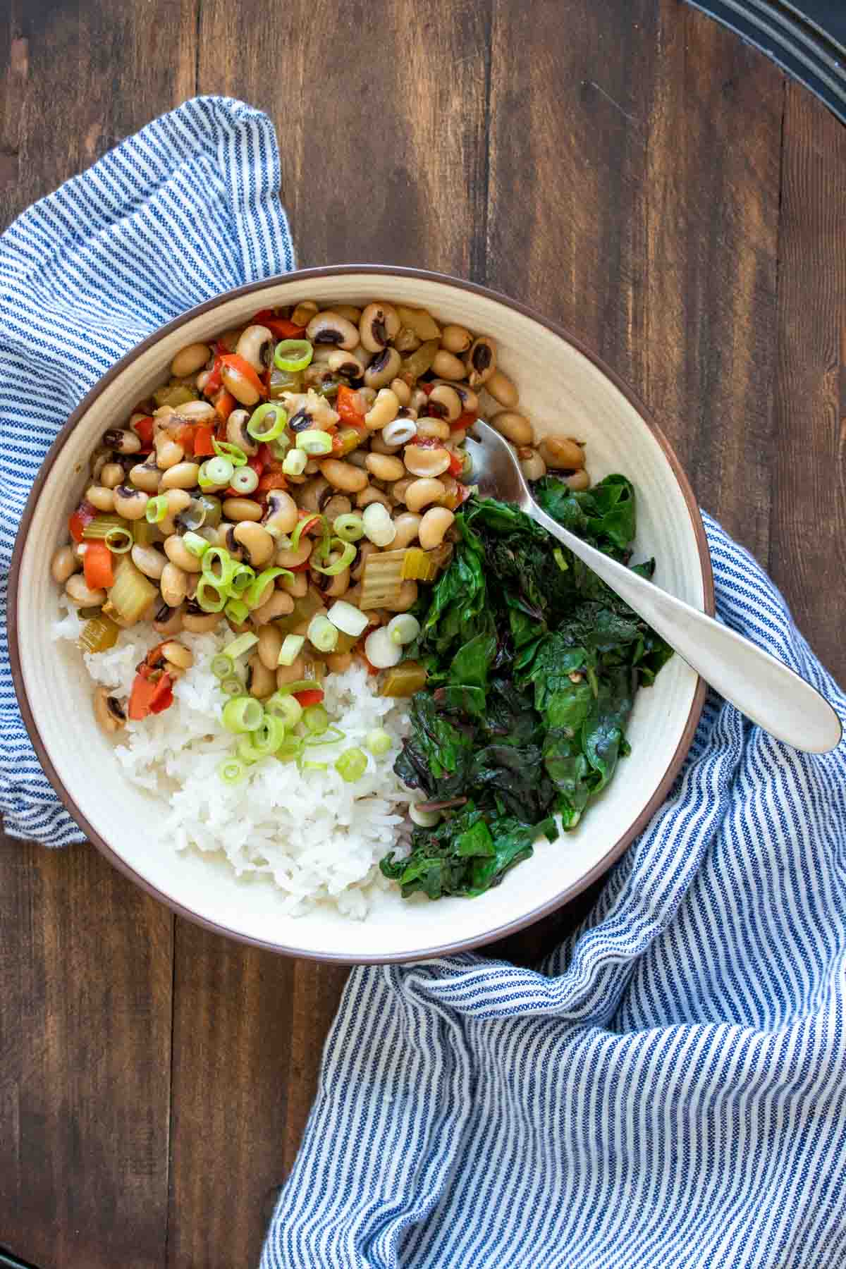 Cream bowl filled with rice, black eyed peas and swiss chard