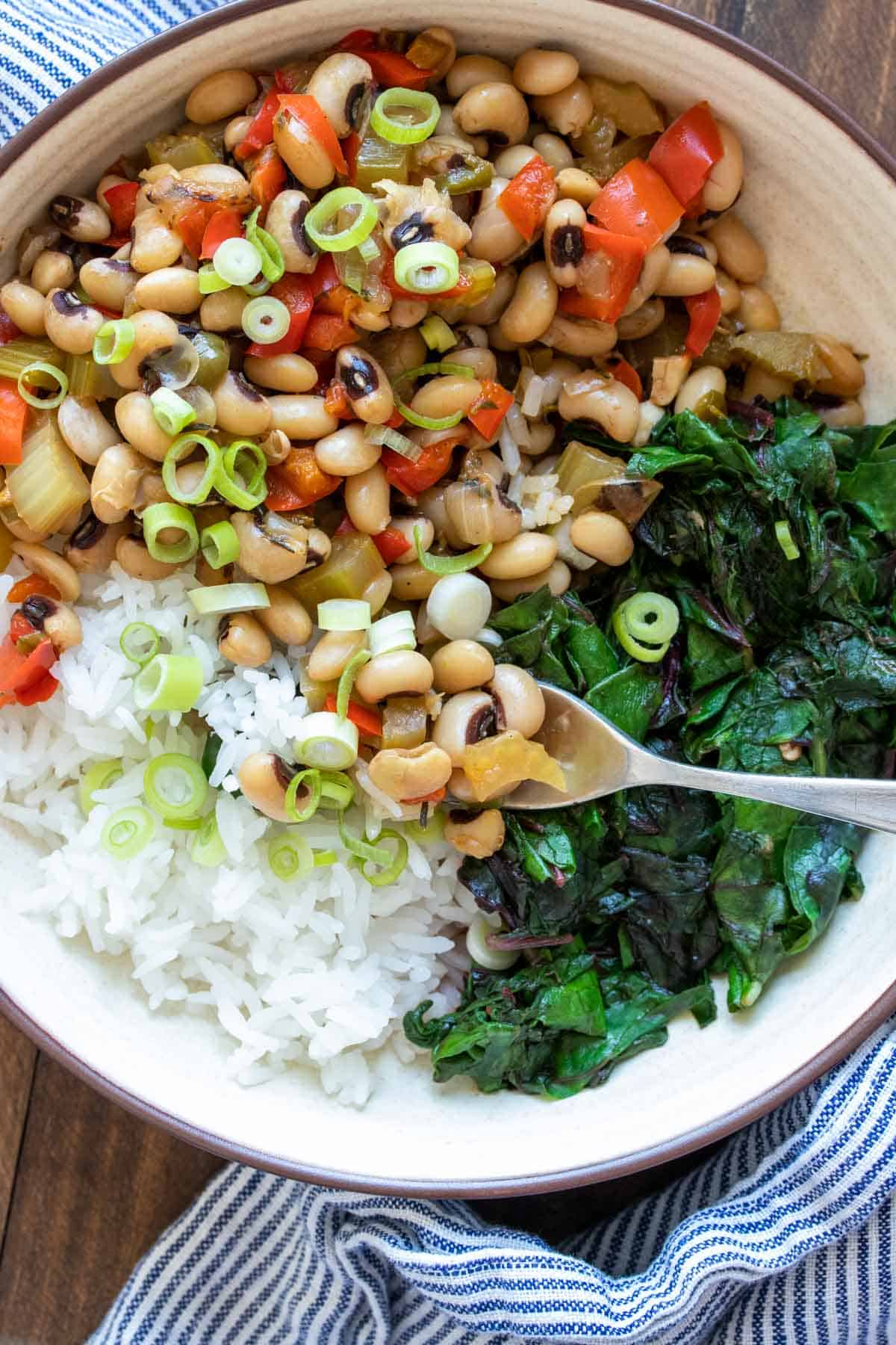 Fork getting a bite of black eyed peas and rice from a bowl filled with a Hoppin John recipe