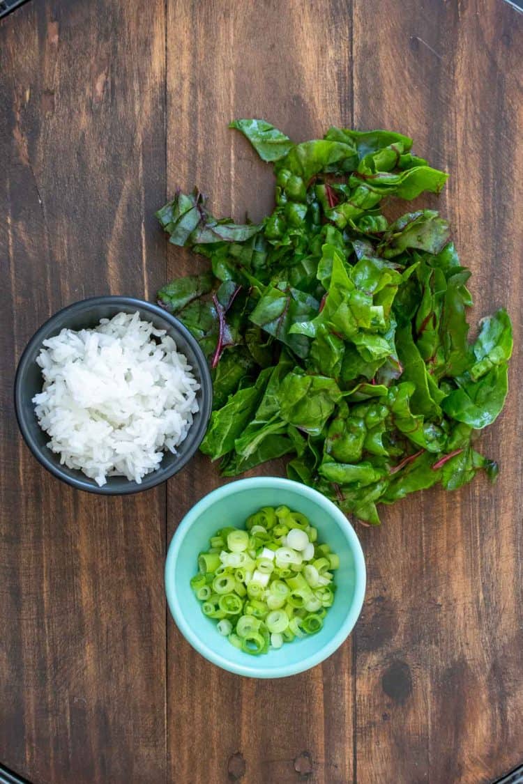 Chard, sliced green onions and rice on a wooden surface