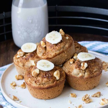 A pile of muffins topped with walnut pieces and banana slices