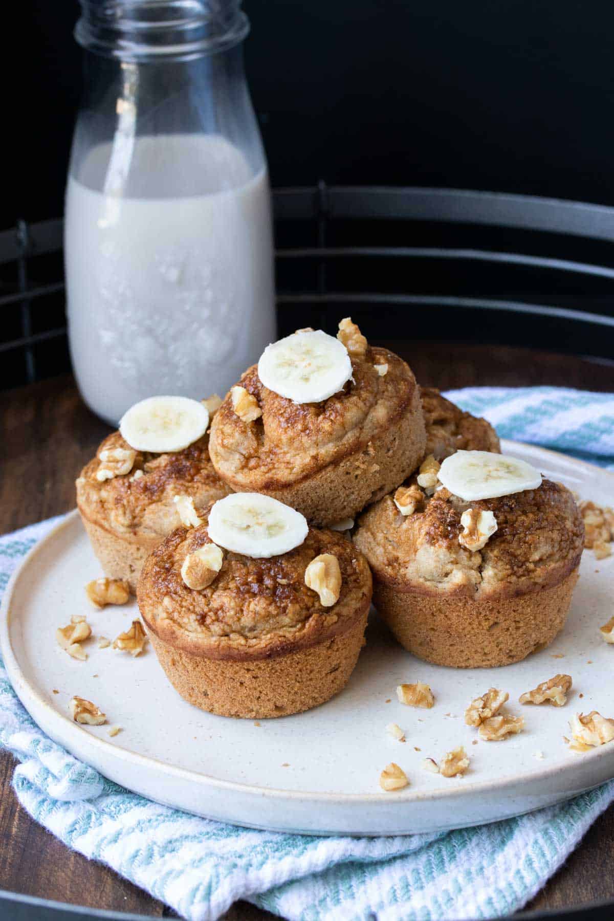 A pile of muffins topped with walnut pieces and banana slices