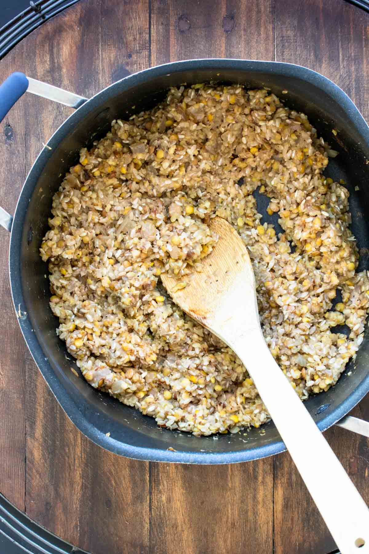 Wooden spoon mixing a rice and bean mix in a pot