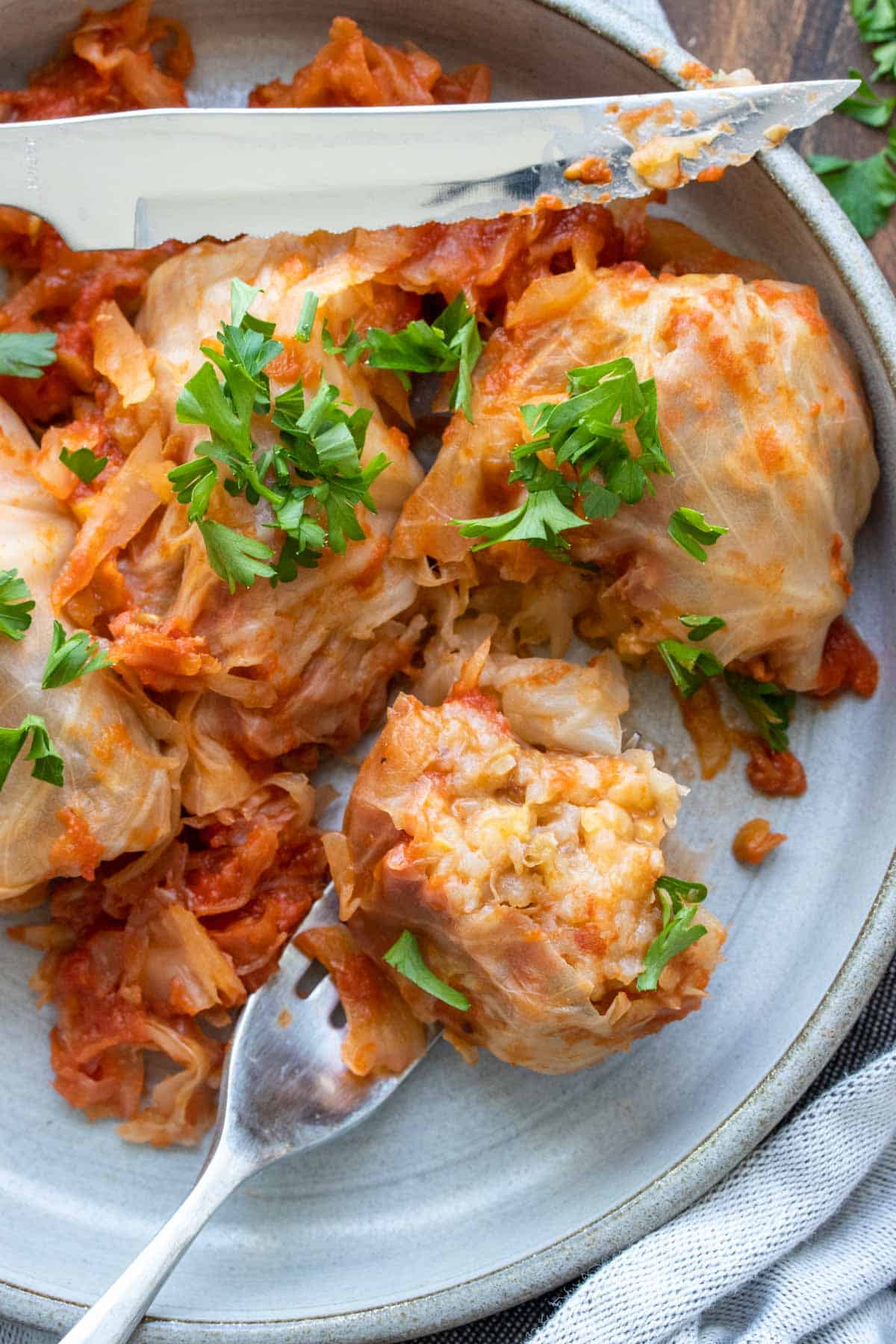 Close up of a piece of cut stuffed cabbage roll on a fork on a grey plate