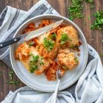 Cabbage rolls on a grey plate covered on tomato sauce and sprinkled with parsley.