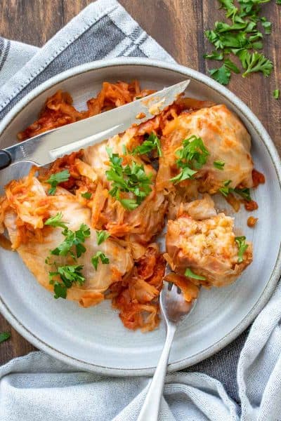 Cabbage rolls on a grey plate covered on tomato sauce and sprinkled with parlsey