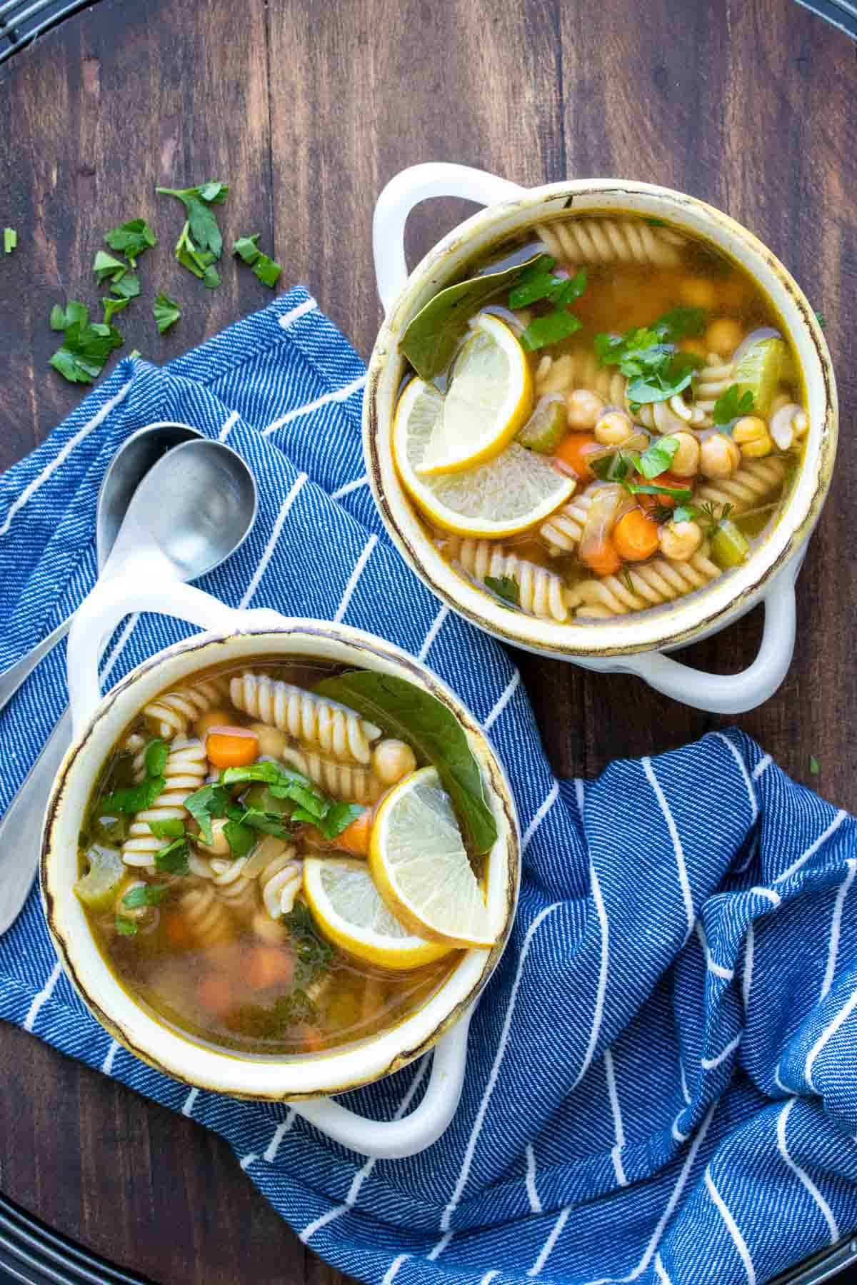 Two white soup bowls filled with chickpea veggie noodle soup