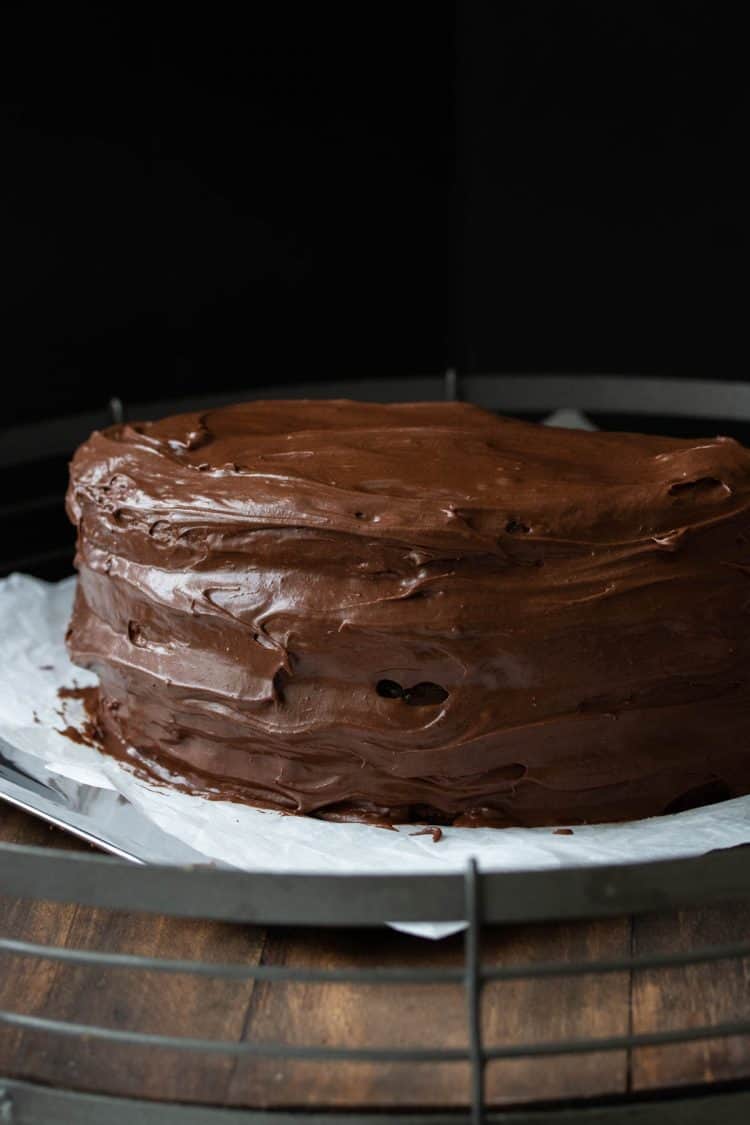 A frosting round chocolate cake on a wooden surface