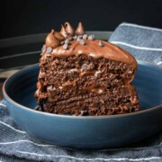 A layered piece of chocolate cake standing up in blue bowl