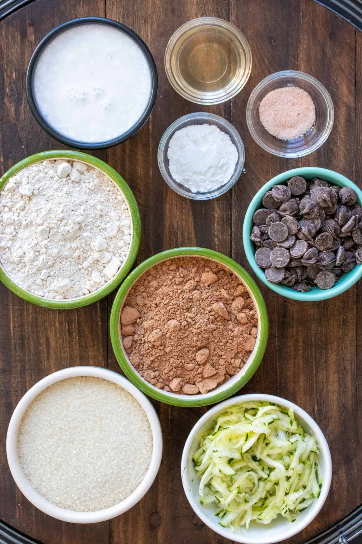 Bowls in different colors and sizes with ingredients to make a chocolate zucchini cake